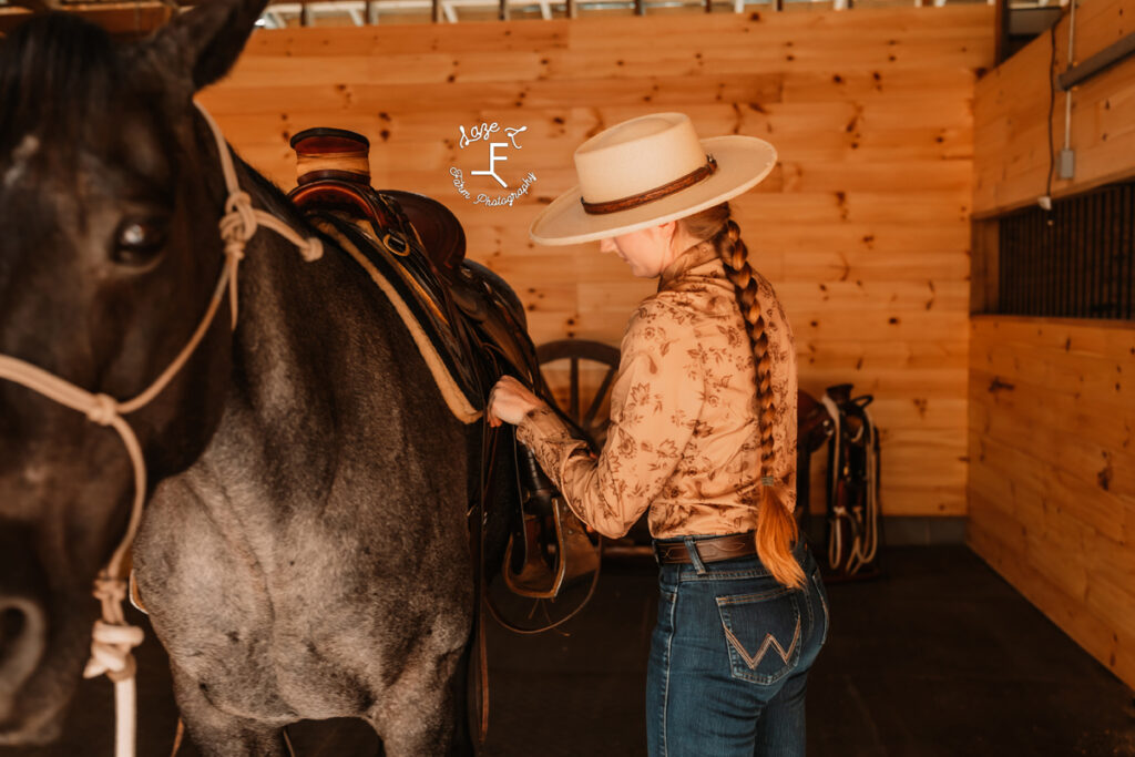 cowgirl saddling horse