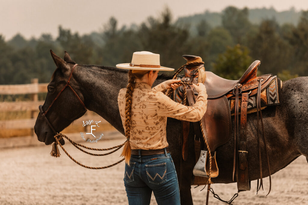 cowgirl saddling horse