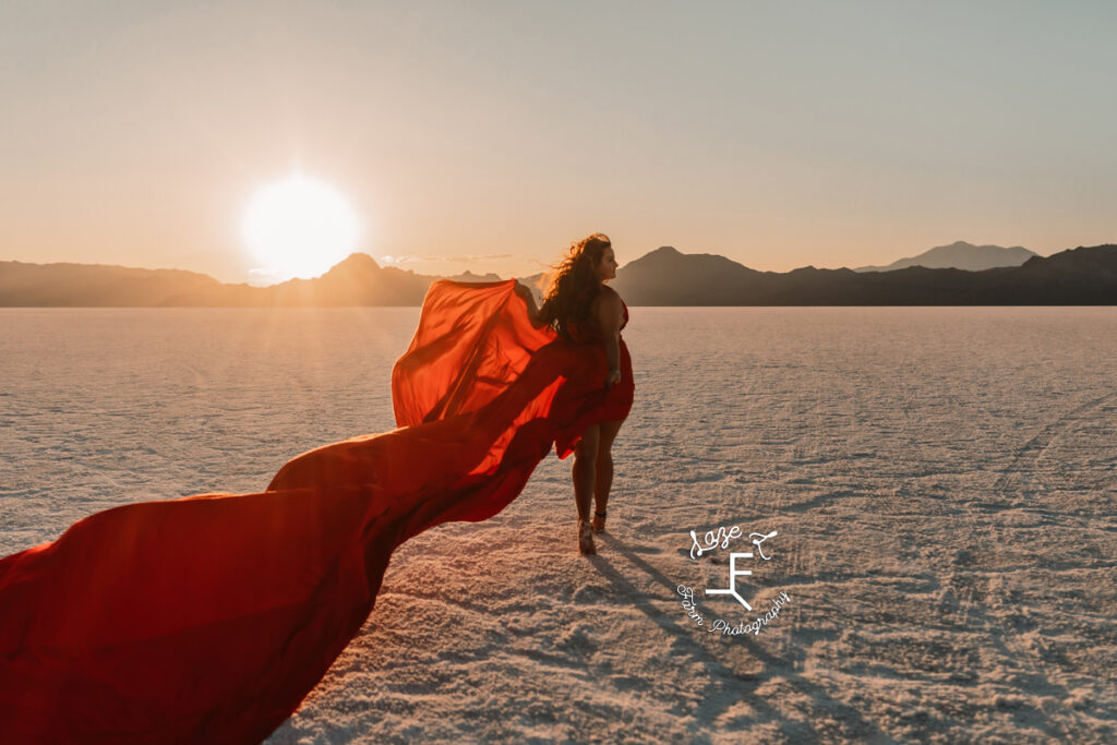 Savannah in red dress walking away from camera with sun over left shoulder