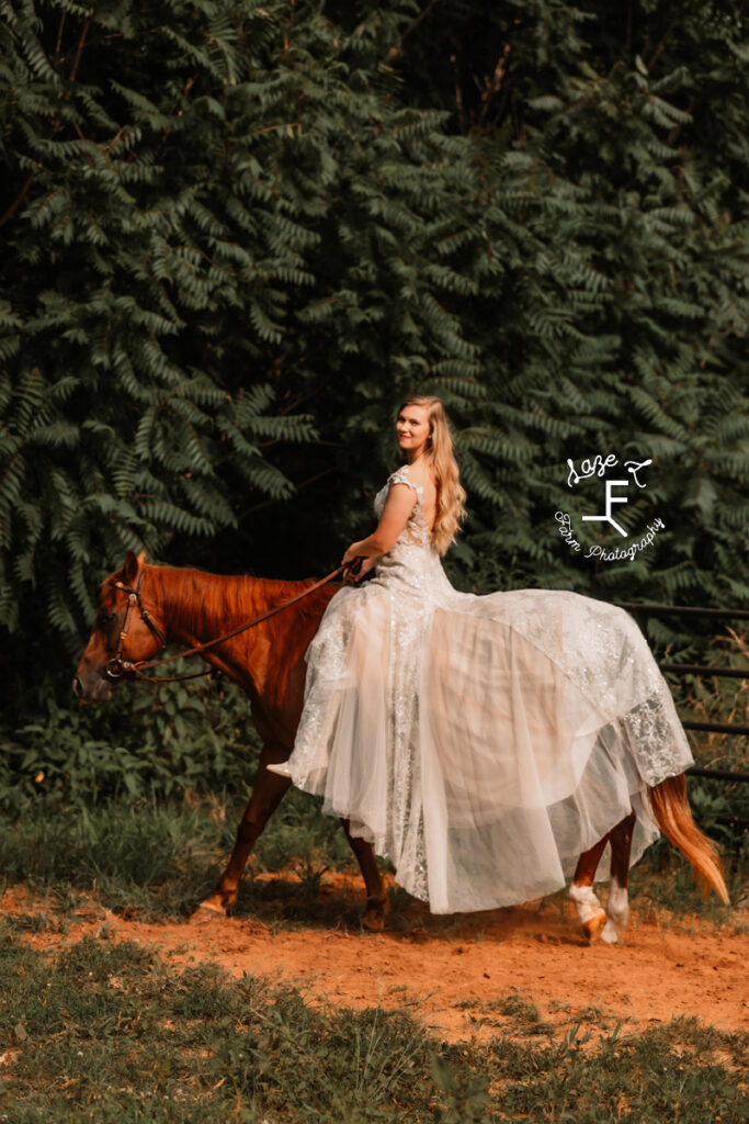 Morgan riding red horse with dress draped over horses back