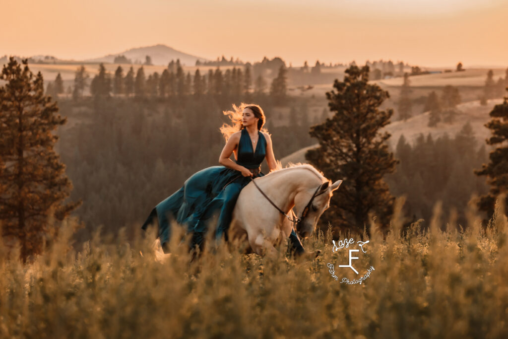 Tevis riding Palomino horse in blue dress at sunset