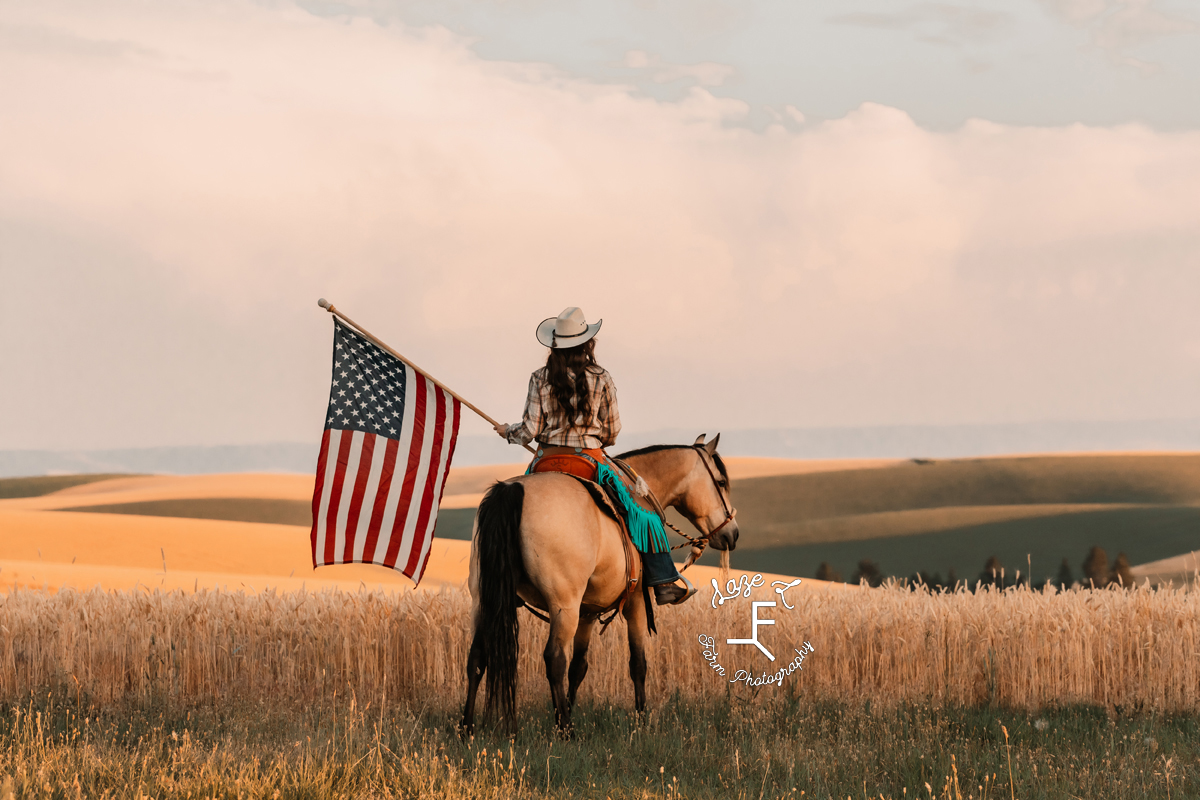 Dakota riding buckskin with American flag at sunset