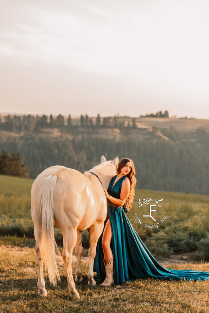 Tevis standing with Palomino horse with mountains in the background