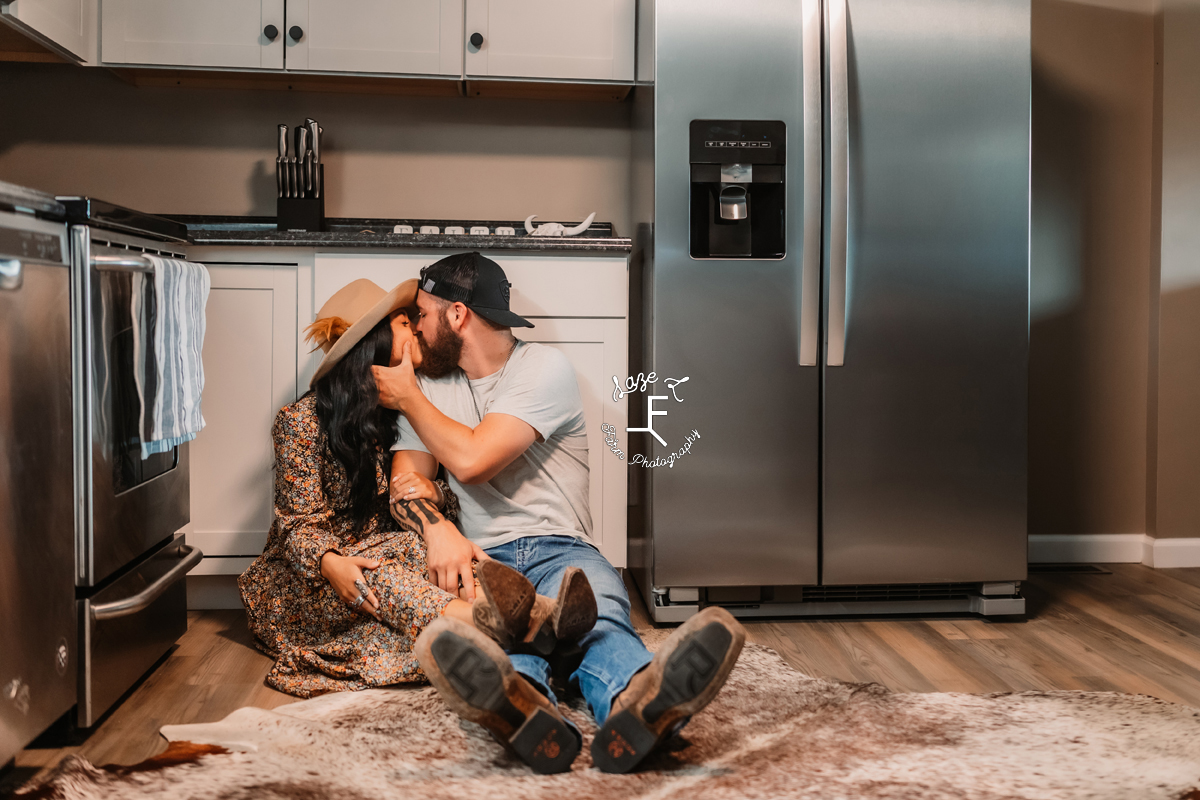 Couple sitting in the kitchen floor kissing