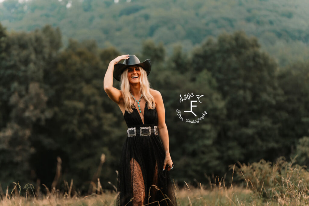 Model in black dress and black hat in a field