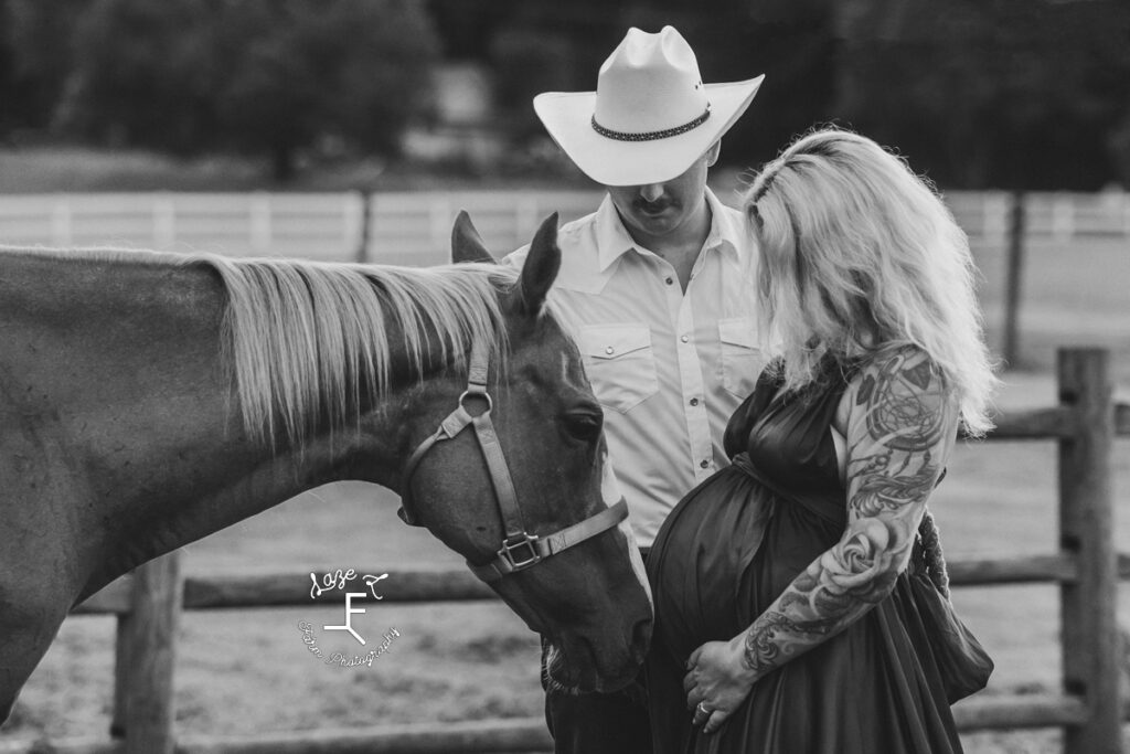 Nike and Nate standing with horse bumping nose to Nike's belly in black and white