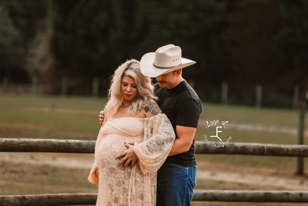 Nike in white lace dress with Nate in cowboy hat touching baby belly