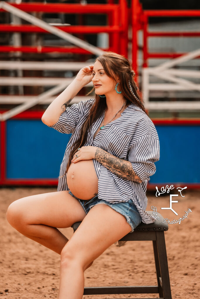 Kirstan in arena on stool with blue jeans and button down shirt