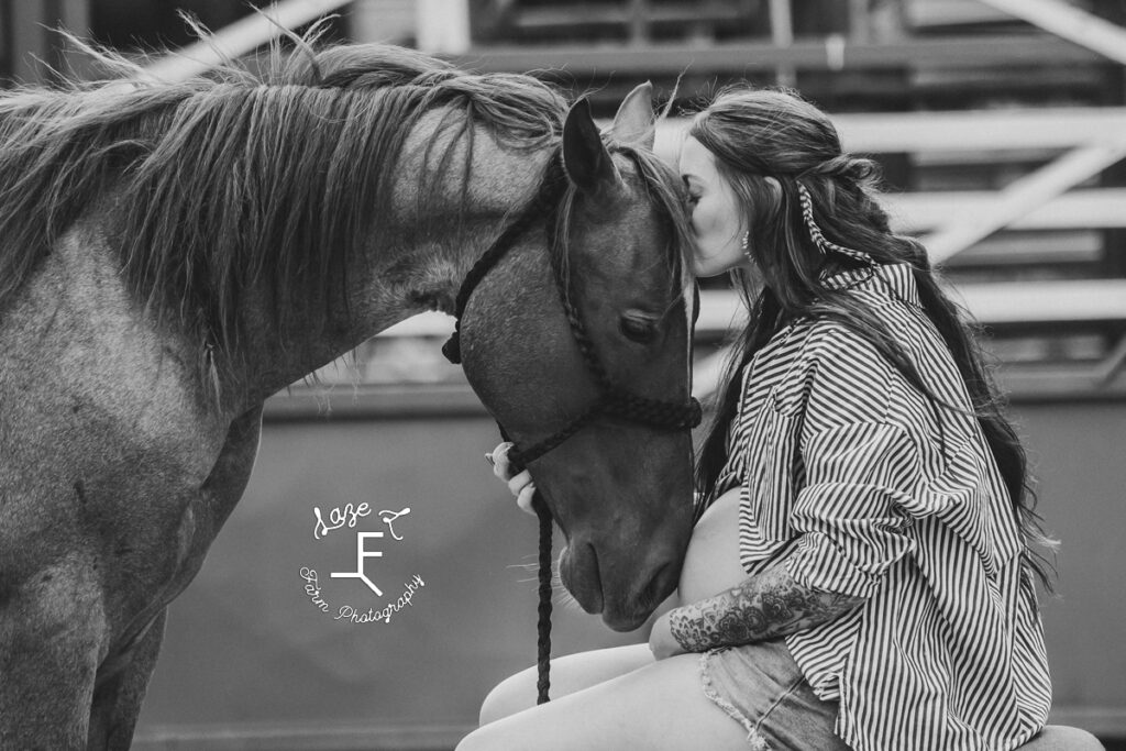 Kirstan kissing horse on head in black and white