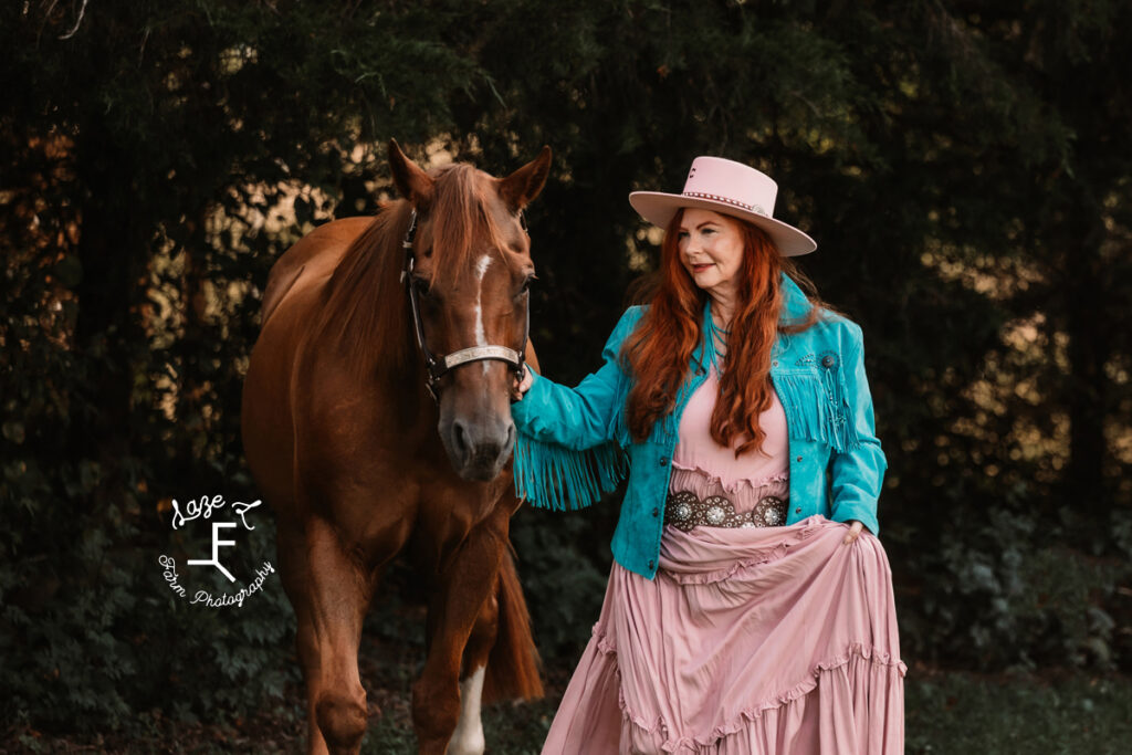 Heather wearing blue fringe jacket walking with her horse