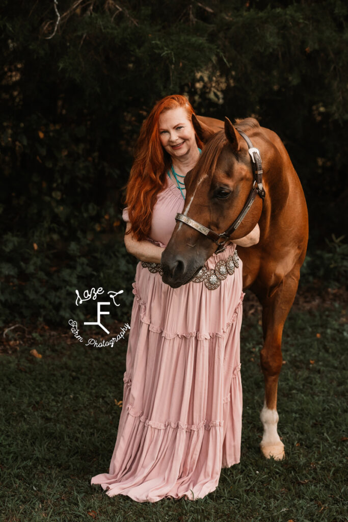 Heather standing with horse in pink dress and no hat