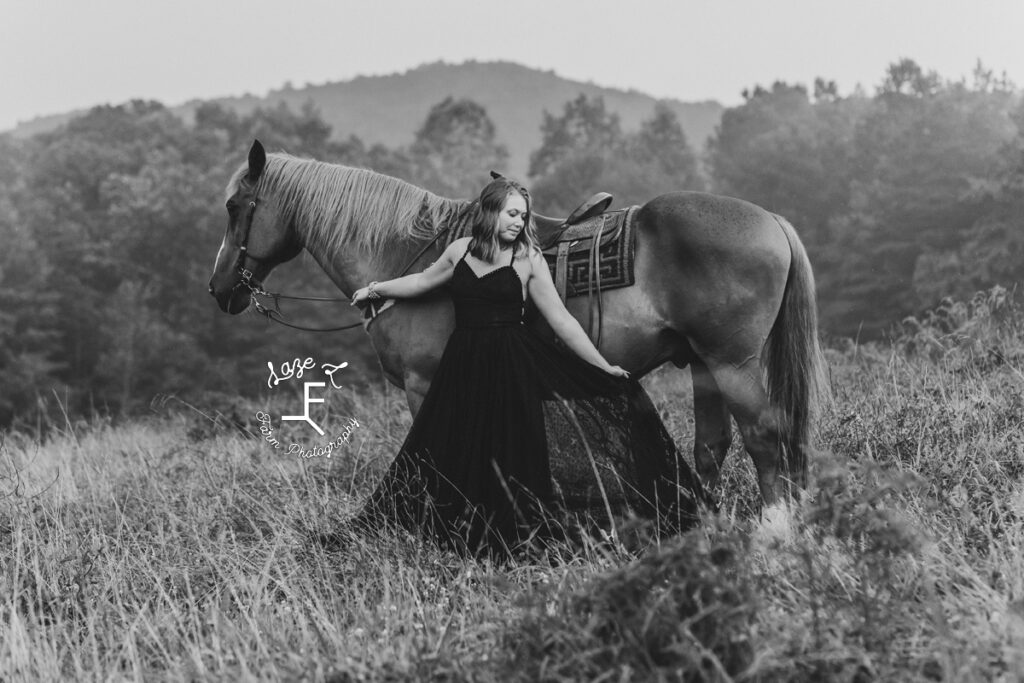 Kayla standing at saddle in black and white