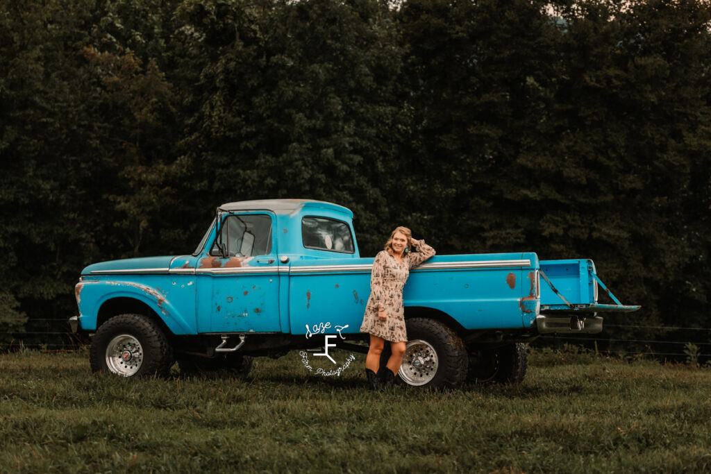 Kayla leaned against old blue truck bed