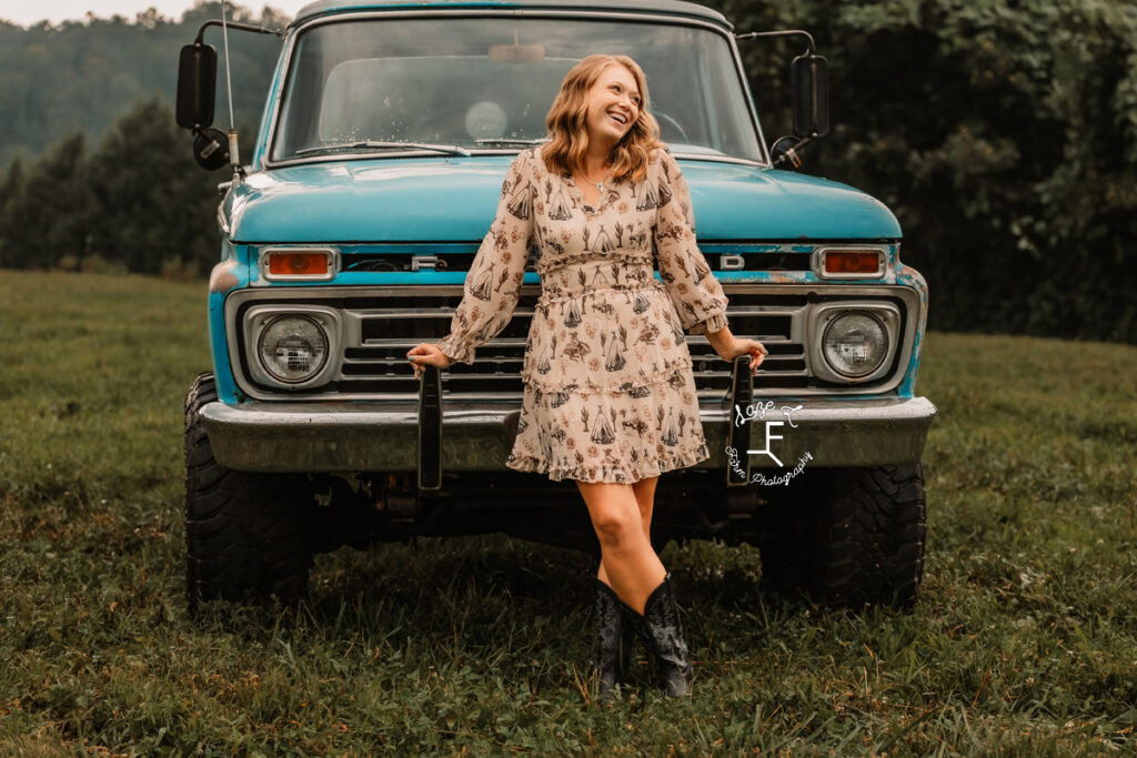 Kayla leaning on front bumper of truck