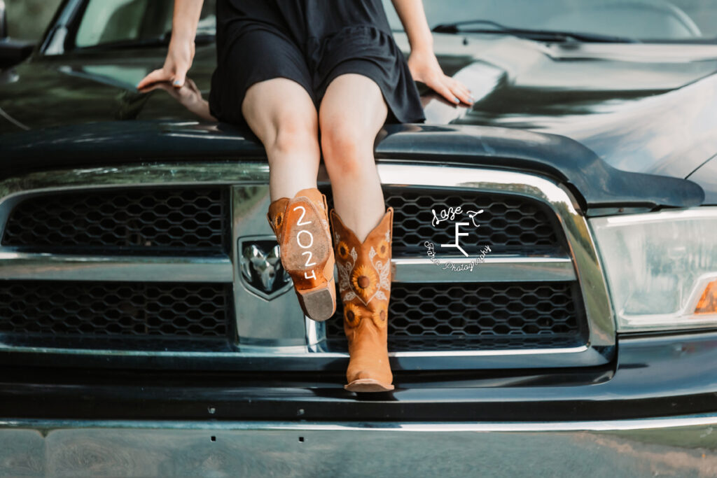 Kendall sitting on hood of truck with 2024 on her boot