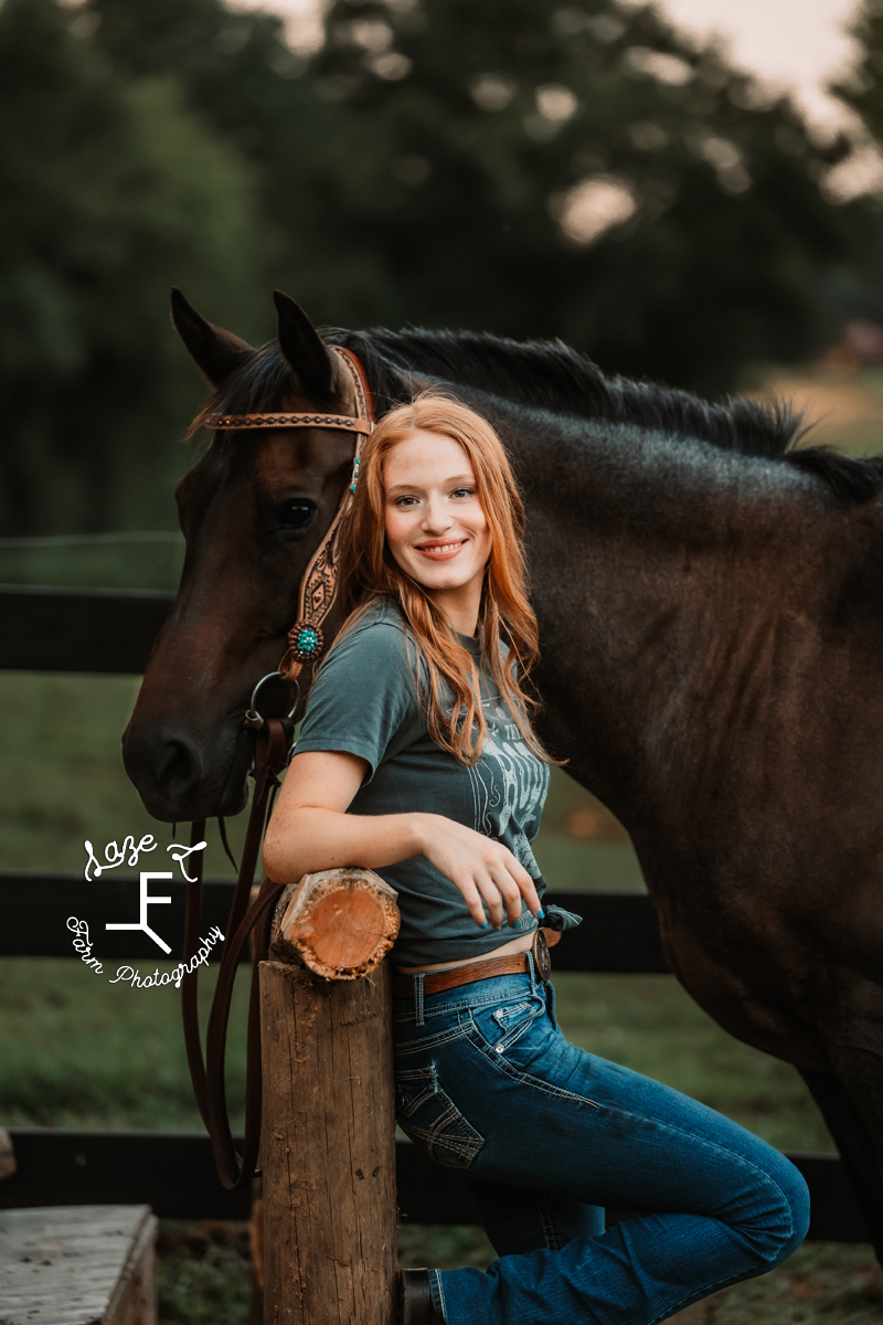 Kendall standing against hitching post with her horse