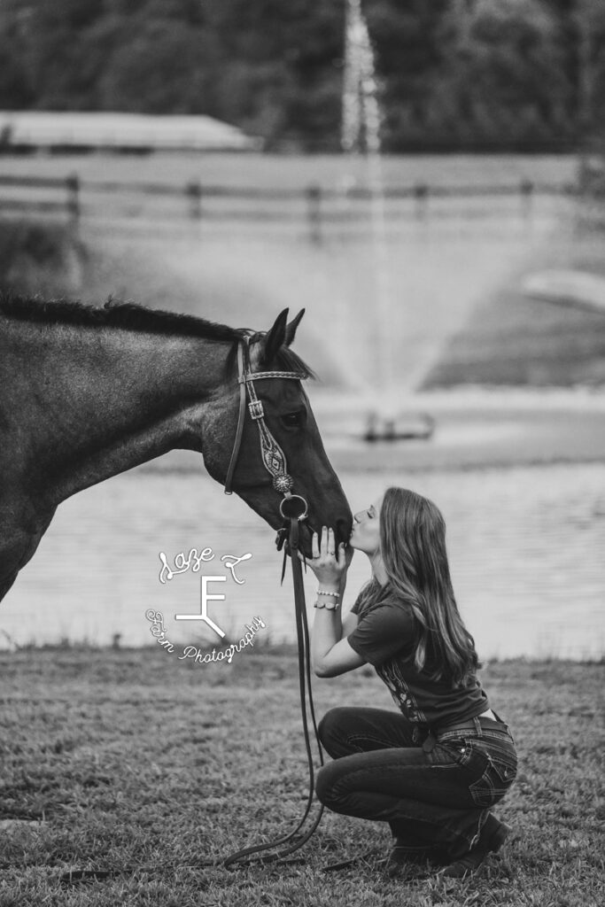 Kendall squatted down kissing her horse's nose in front of fountain