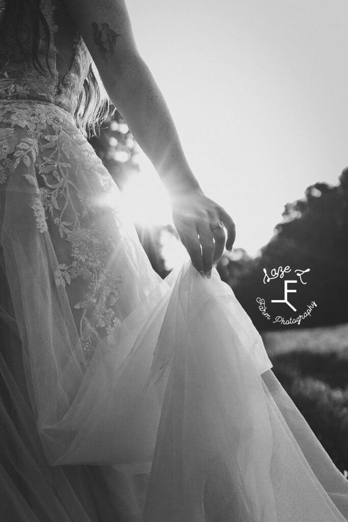 dress being held by left hand showing engagement ring in black and white