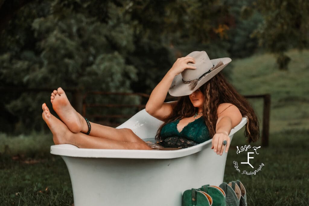 Savannah witting with feet propped out of water in bath tub with cowboy hat