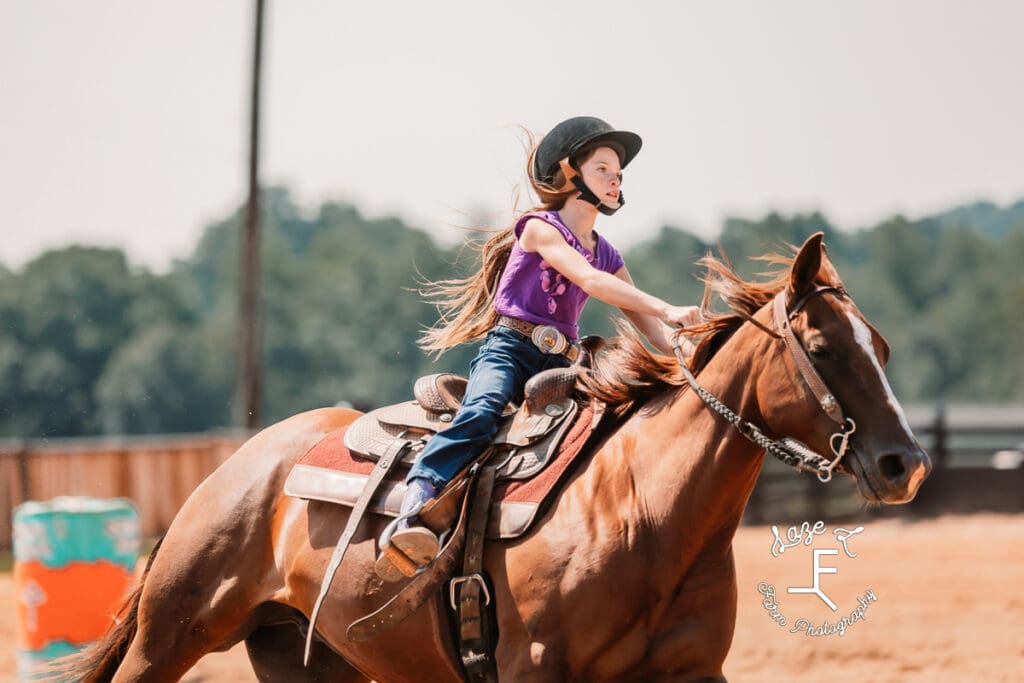 girl in purple shirt on brown horse