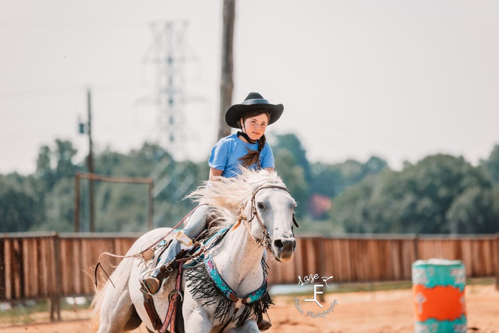 girl in blue shirt on gray horse