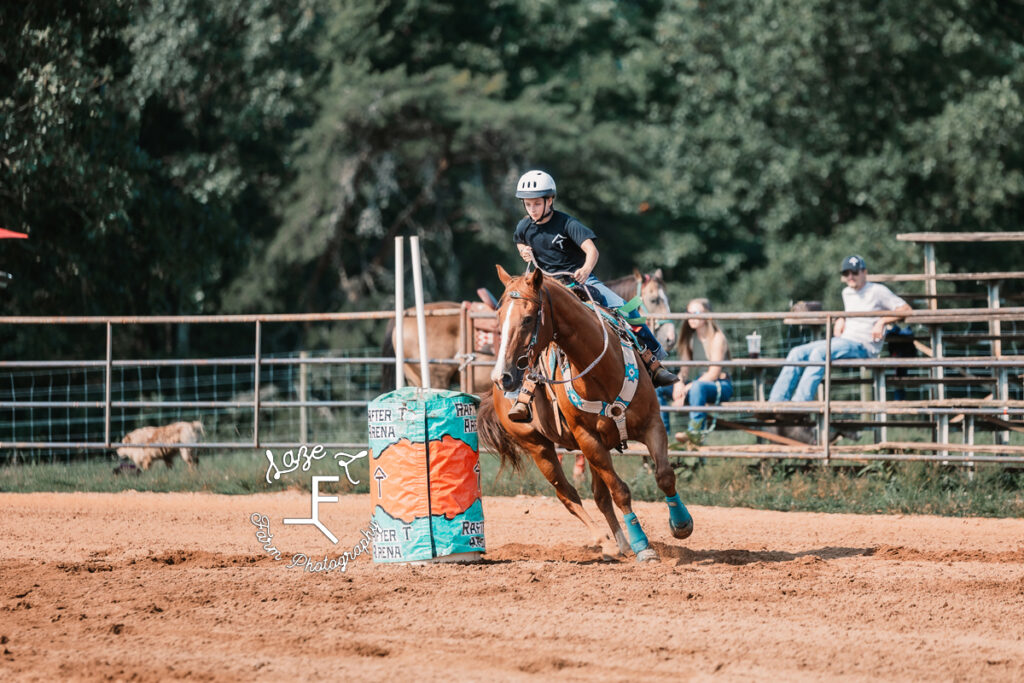 girl in black shirt on brown horse rounding barrel