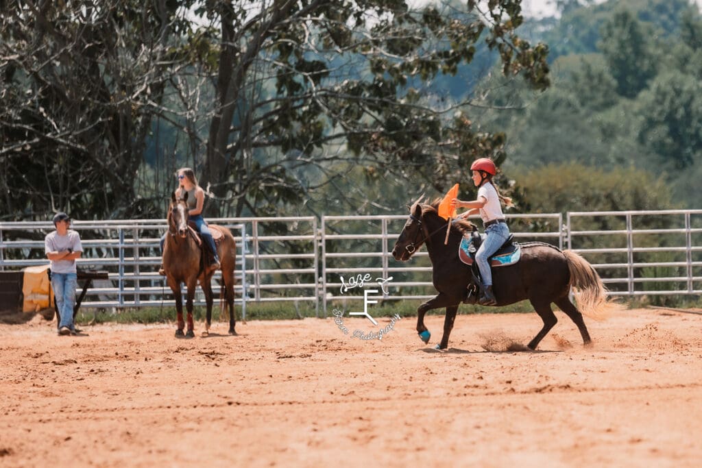 girl carrying orange flag on pony