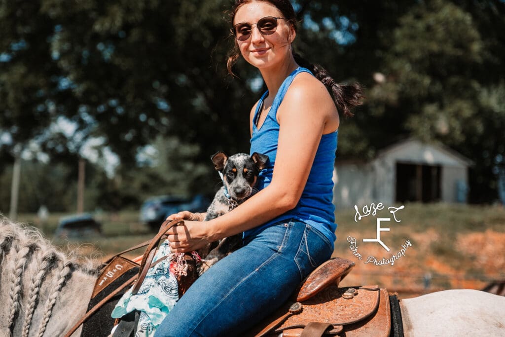 girl on horseback with puppy in saddle with her