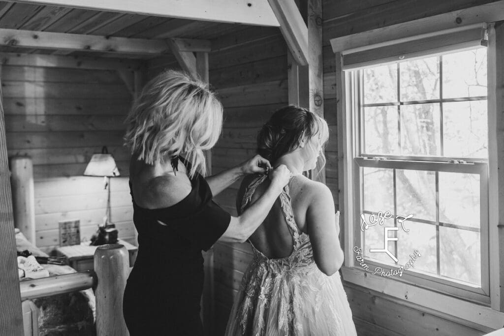 mother of the bride helping bride into her dress