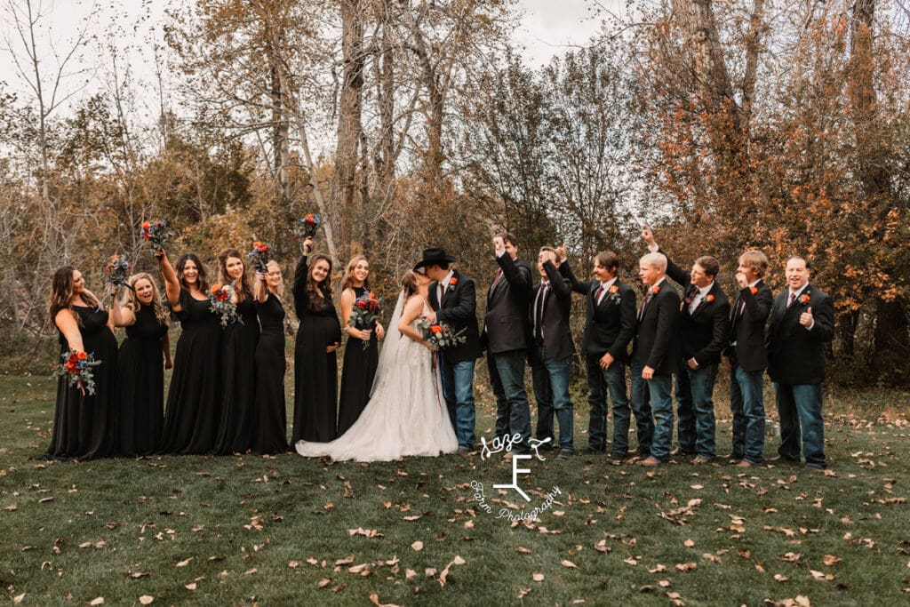 Bride and groom kissing with bridal party cheering