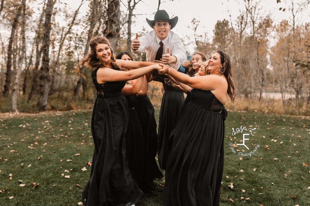 bridesmaids tossing groom in the air