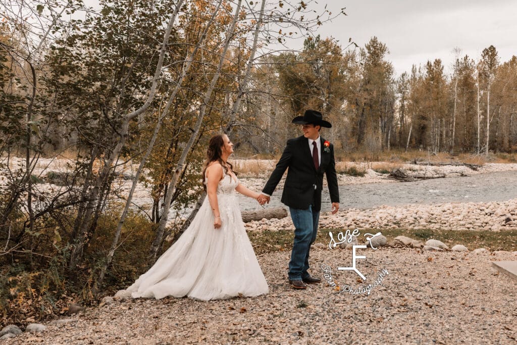 Bride and groom walking by river