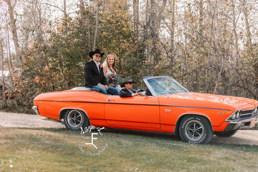 Bride and groom in orange convertible 69 Chevelle