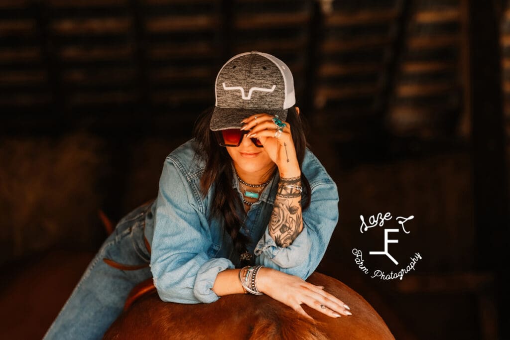 Halle sitting on Gus backwards touching hat showing jewelry