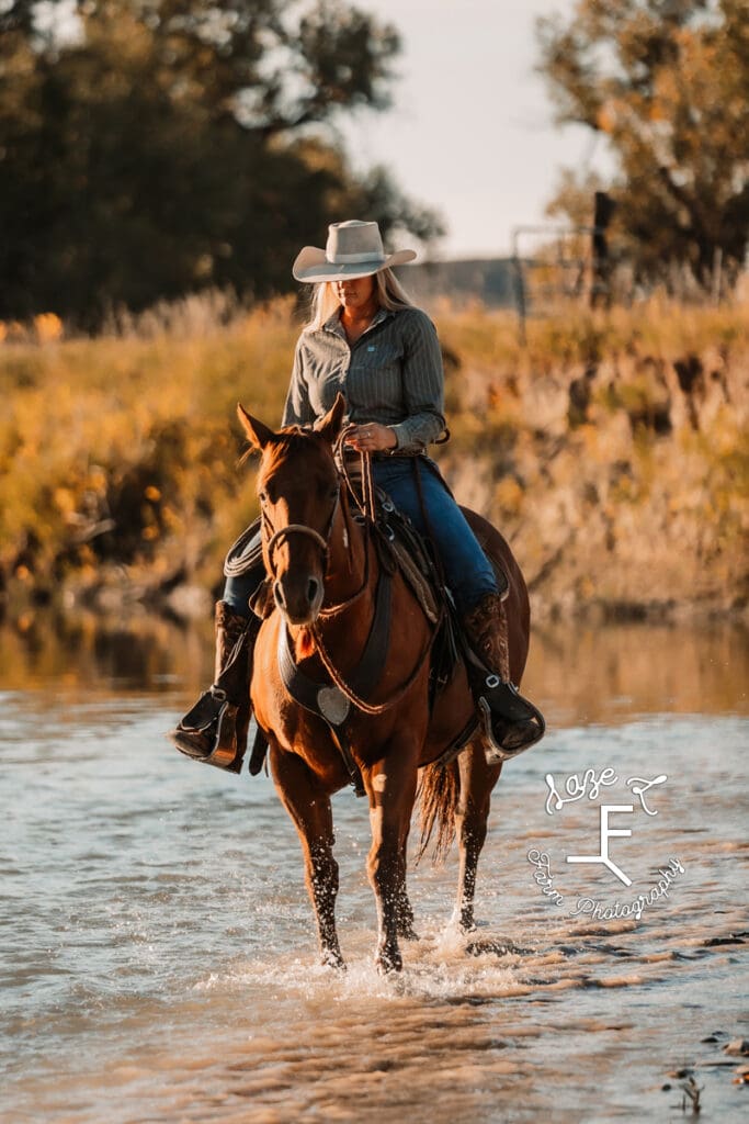 Cowgirl on brown horse walking in water