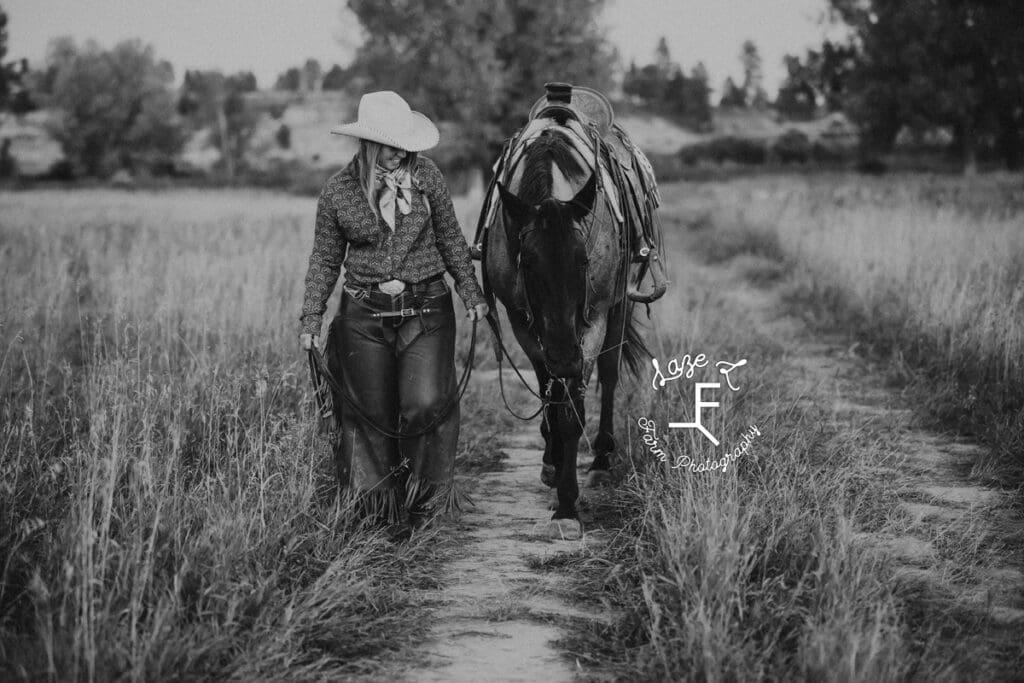 Cowgirl 2 walking with roan horse in black and white