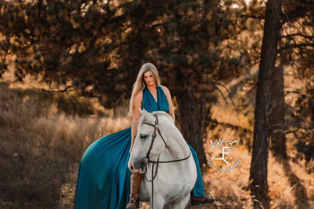 Cowgirl 1 under trees in turquoise dress on grey horse