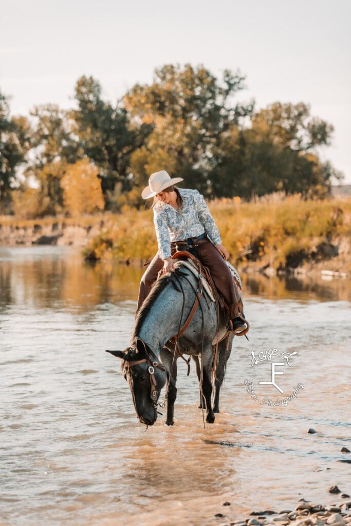 Cowgirl 2 on roan horse walking in water