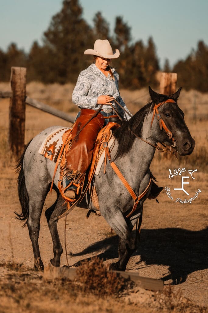 Cowgirl 2 wearing light blue shirt on roan horse