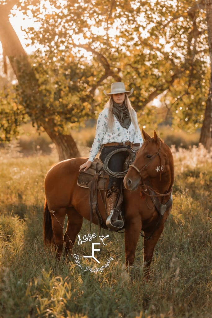 Cowgirl 1 on brown horse under trees in a pasture