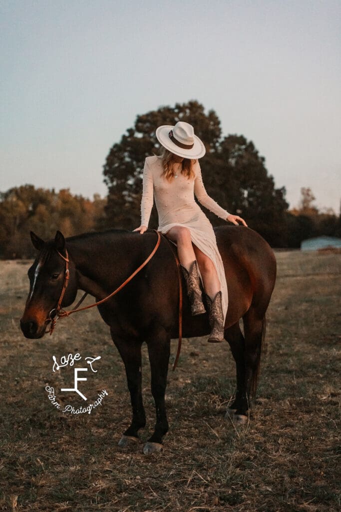 cowgirl in pearl dress looking down on horseback