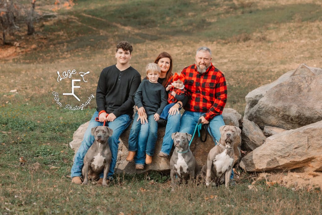 Childers family sitting on rocks with 3 dogs