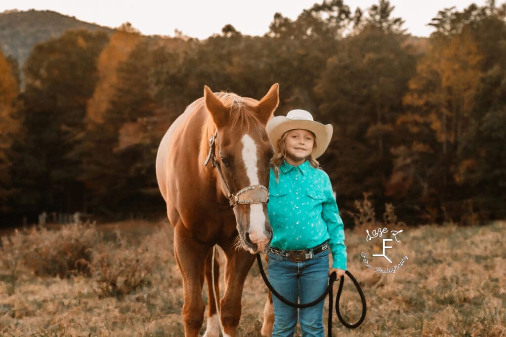 little cowgirl standing with her horse