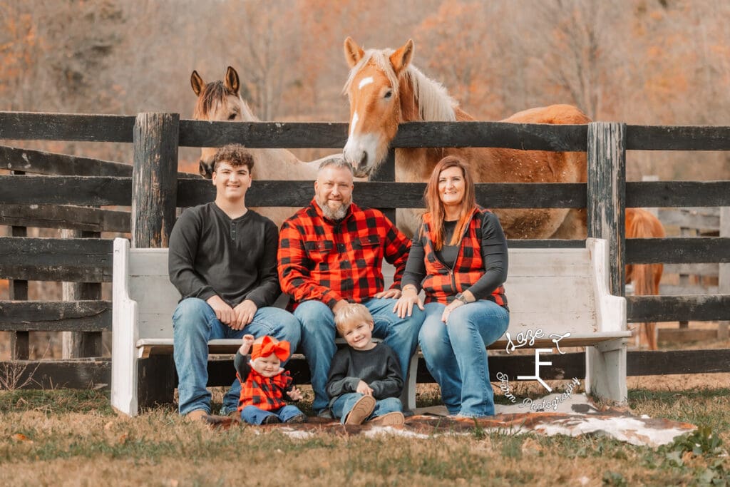 Childers family sitting on white church pew with horses behind them.