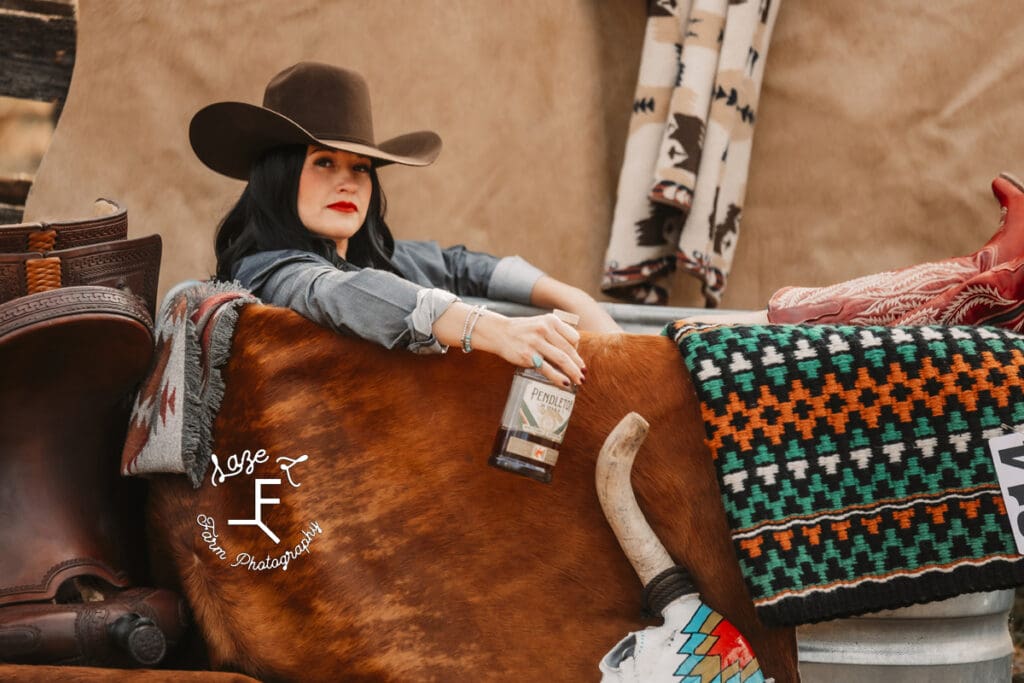 Elizabeth sitting in water trough with red boots kicked up on side 