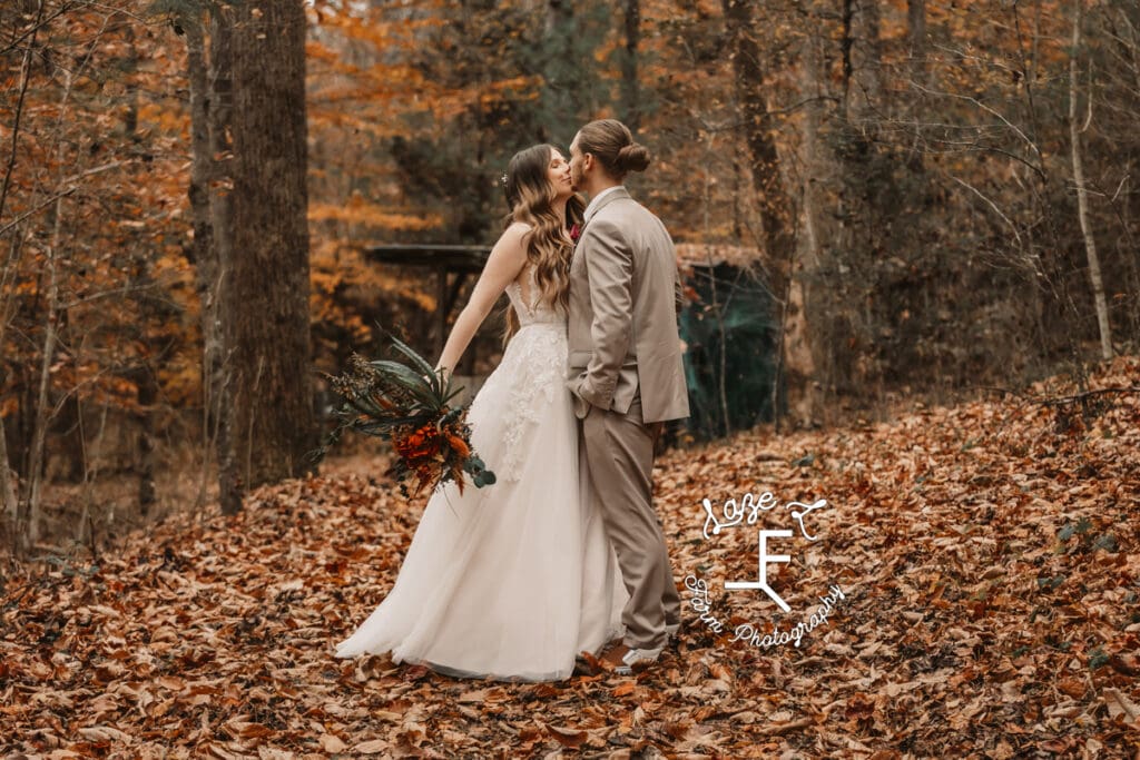 Bride and groom kissing in orange woods