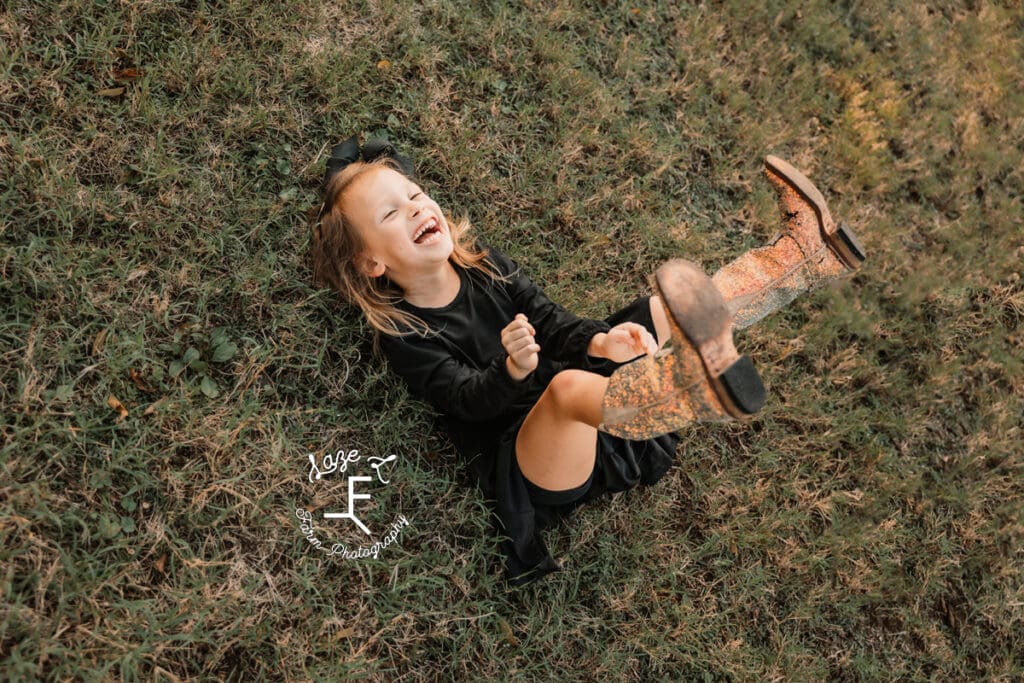 little girl laying on ground laughing