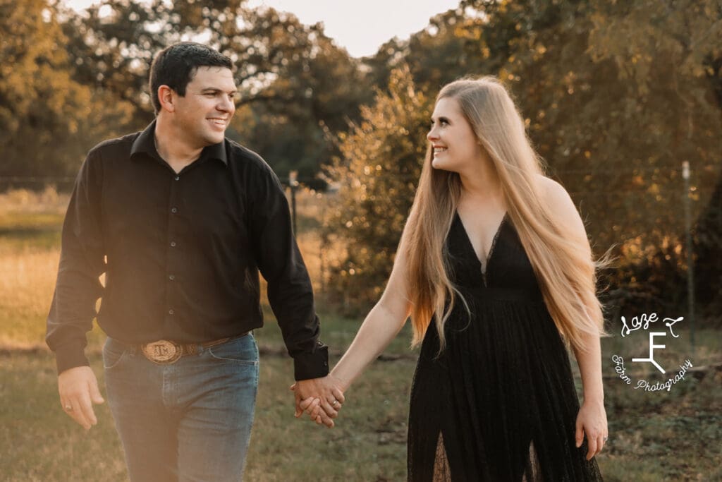 husband and wife in black walking holding hands