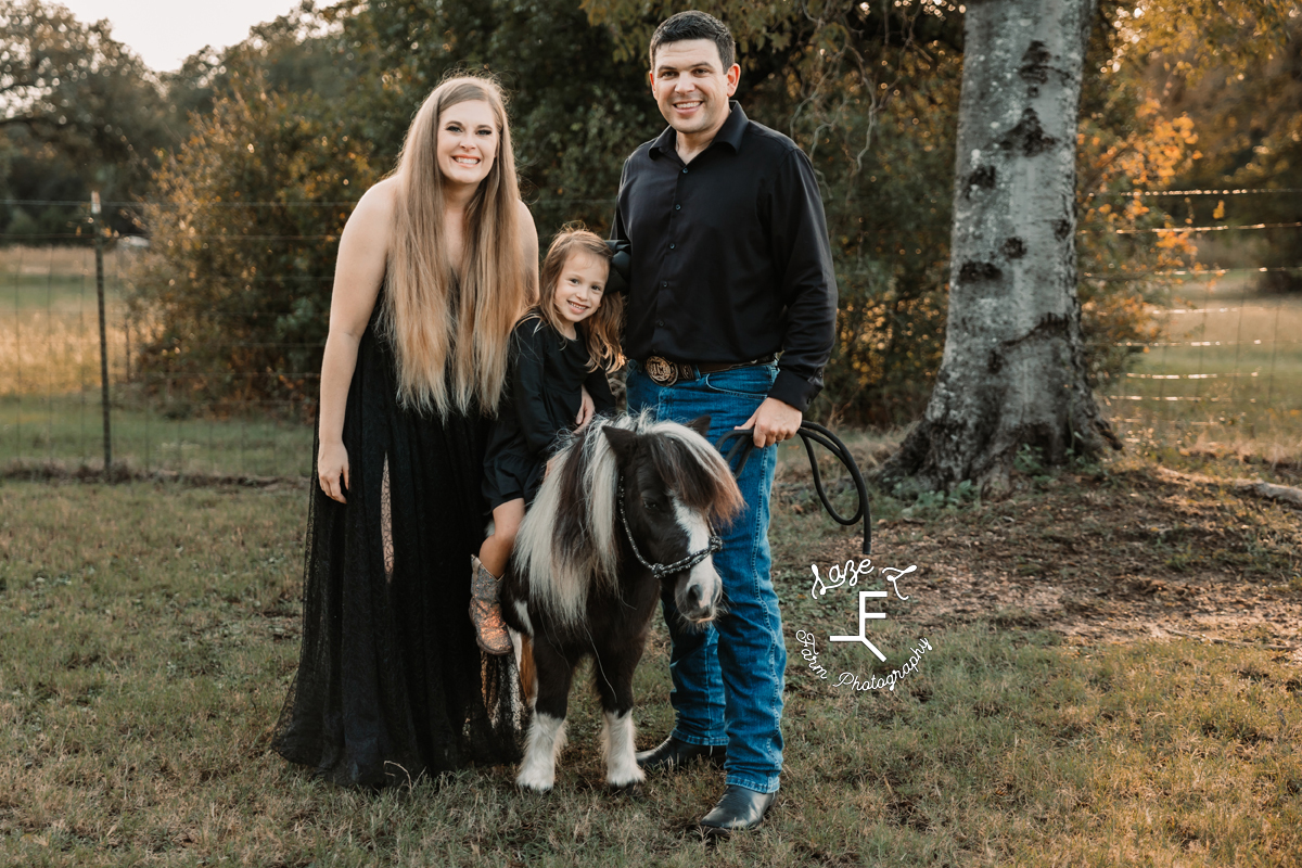 Family of 3 with little girl sitting on pony