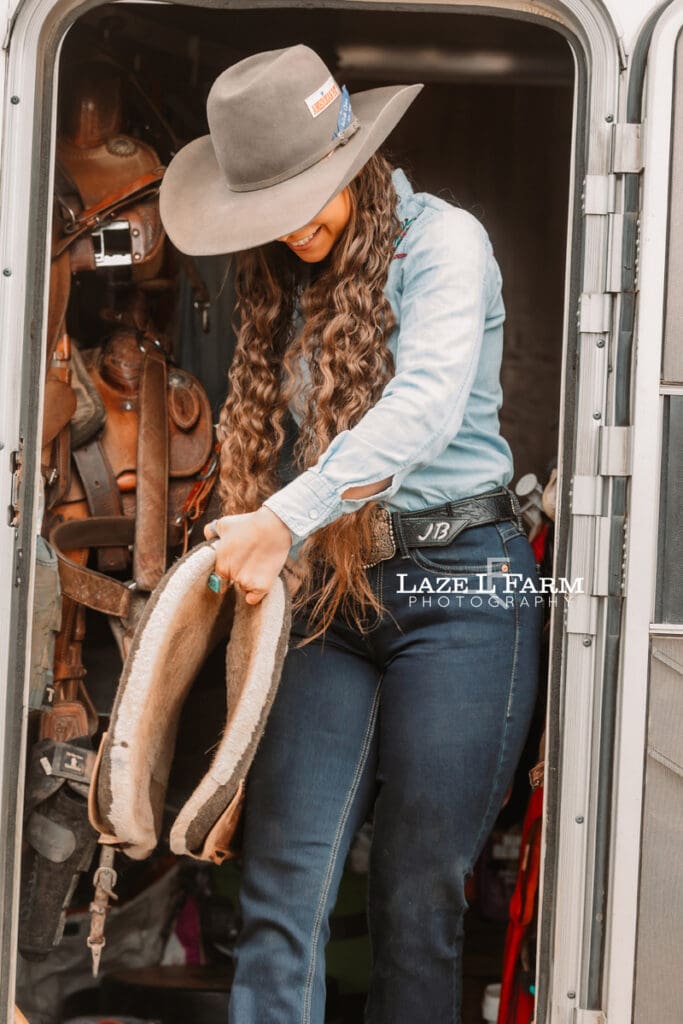 cowgirl saddling her horse
